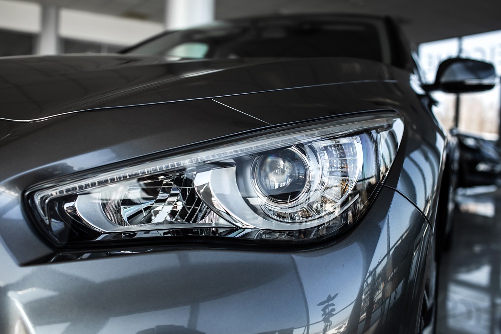 Close-up view of a modern car's front left headlight, highlighting the detailed design and metallic grey body, expertly maintained by Mobile Car detailing Hammond in a well-lit showroom.