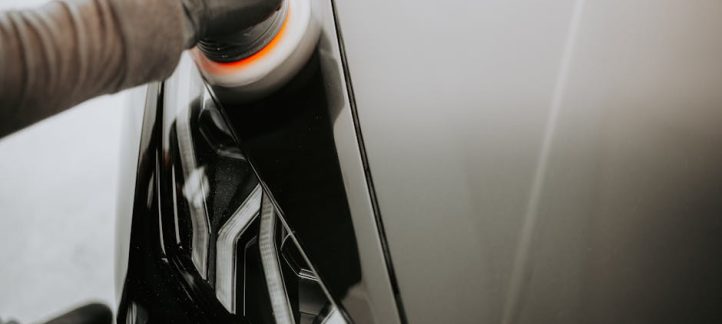 Person polishing a car headlight lens during a professional headlight restoration service