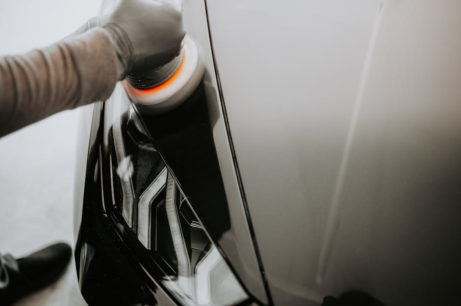 Person polishing a car headlight lens during a professional headlight restoration service