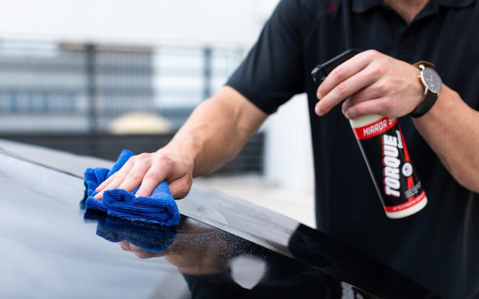 Detailer hand washing a vehicle with a microfiber mitt in a New Orleans driveway