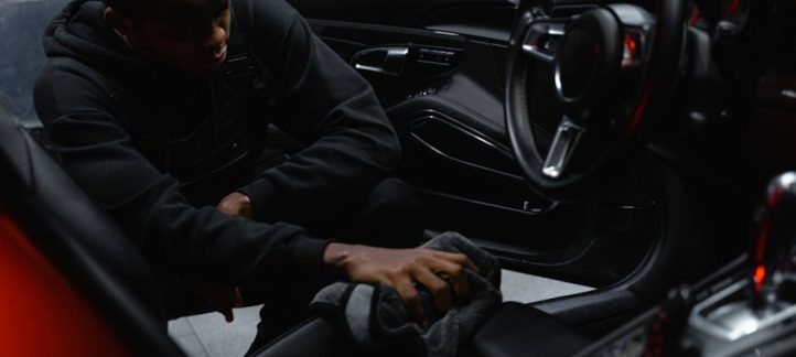 Detailer vacuuming and deep cleaning the interior of a car with professional equipment