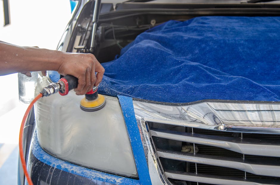 Professional technician polishing a car headlight with an electric buffing tool during headlight restoration service in New Orleans
