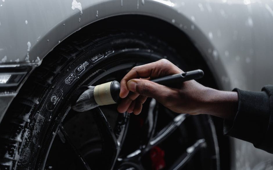 Professional detailer cleaning brake dust from a car wheel with a specialized brush in New Orleans
